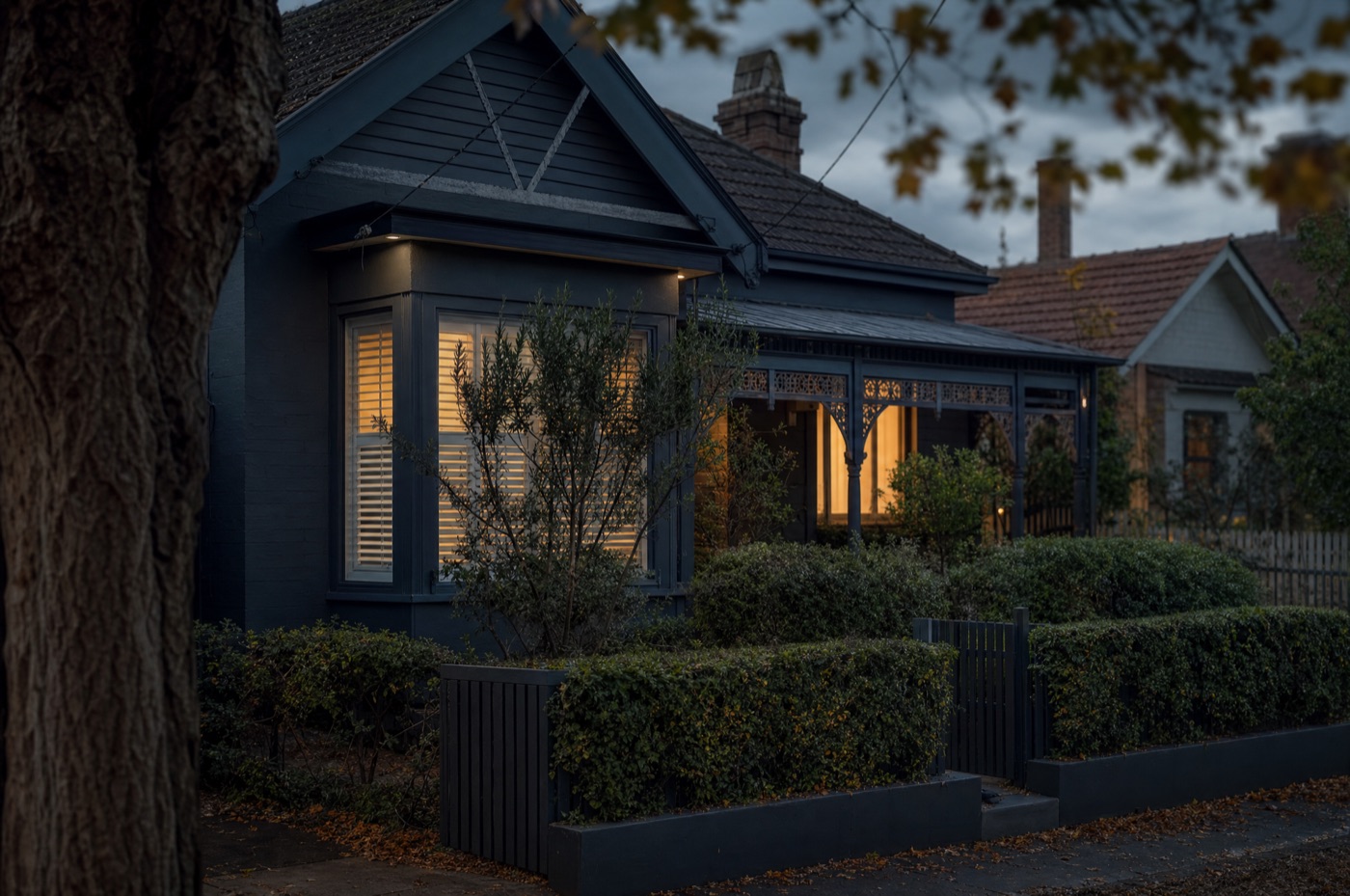 A quiet suburban Melbourne family home at dusk with warm interior lights, representing the family home in a property settlement