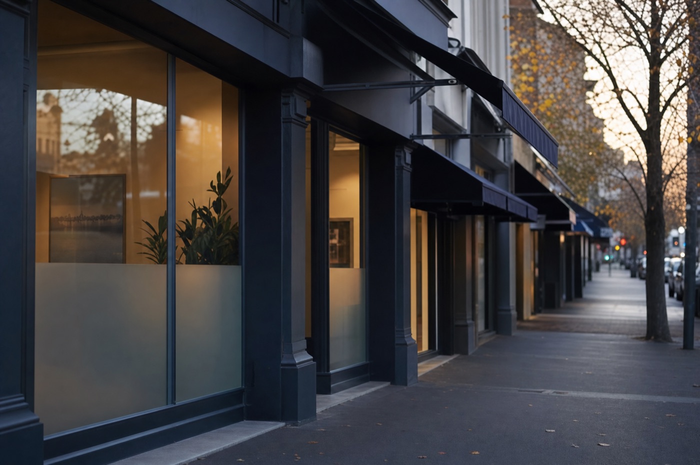 A row of uniform franchise-style retail shopfronts along a Melbourne street at early morning